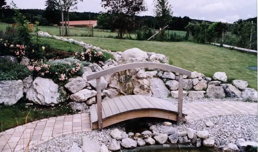 Steingarten mit Holzbrücke über einen Bachlauf